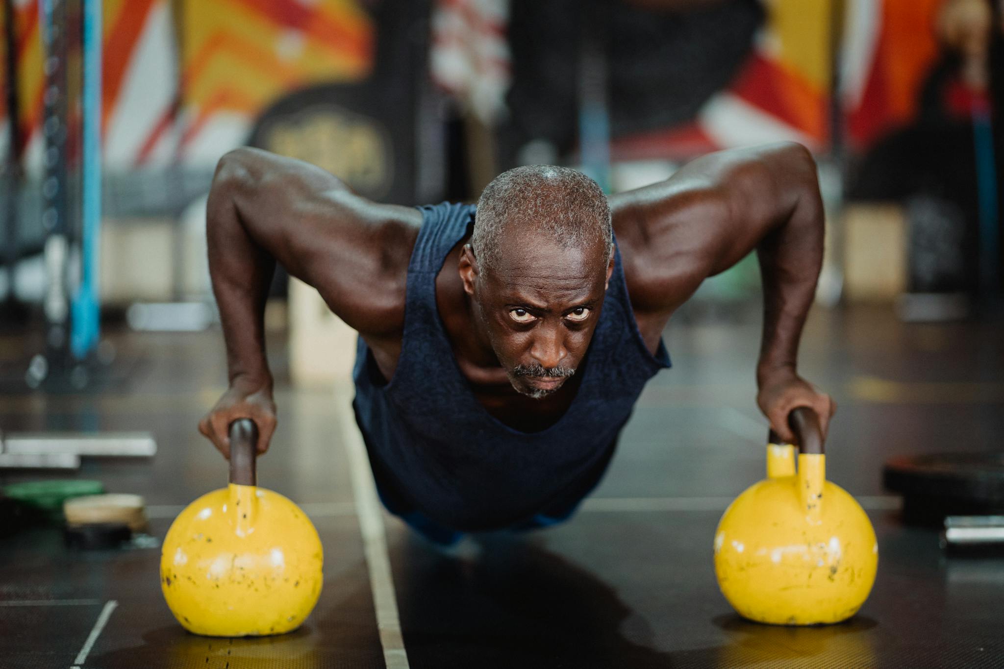 Determined man performing push-ups with kettlebells at gym, showcasing strength and focus.